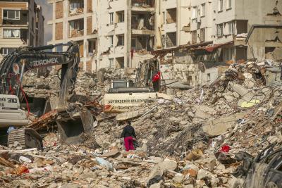 Un homme marche parmi les débris alors que des excavatrices démolissent les restes d’un bâtiment détruit suite au tremblement de terre à Samandag, dans le sud de la Turquie, le 22 février 2023. (Photo AP/Emrah Gurel) 