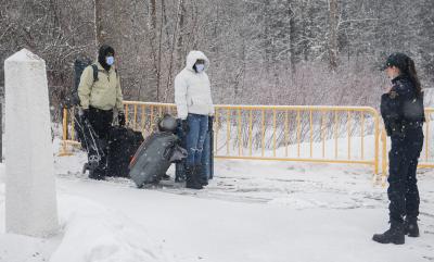 Un agent de la GRC arrête des personnes qui entrent au Canada par le chemin Roxham à la frontière canado-américaine à Hemmingford, au Québec, le 25 mars 2023. (LA PRESSE CANADIENNE / Graham Hughes)